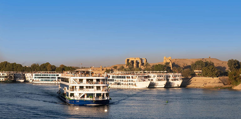 Nile Cruise Boat On River With Ruins Of Kom Ombo Temple