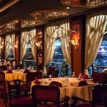 Fine dining tables set by the window for a Nile cruise with a belly dancer and panoramic river views