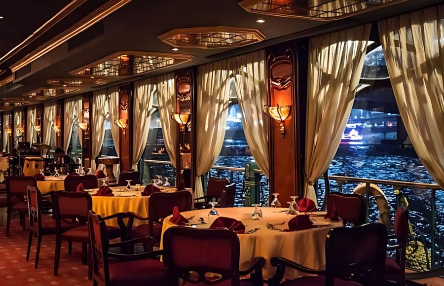 Fine dining tables set by the window for a Nile cruise with a belly dancer and panoramic river views