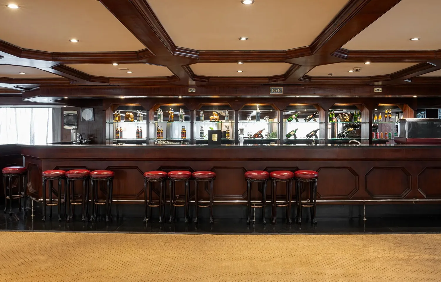 The interior bar of a cruise ship featuring a long, dark wood