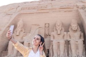 A tourist snapping selfies at Abu Simbel Temple. Perfect for package tours to Egypt from Australia. A tourist taking a selfie in front of the Abu Simbel Temple, a popular destination for Egypt holidays from Australia.