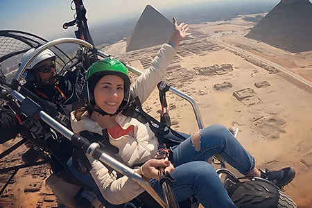 A happy traveler enjoying a Cairo paragliding tour high above the Egyptian desert