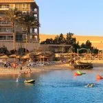 People enjoying the beach area with sun shades and lounging chairs at a resort on the Red Sea, showing a sunny hotel and resort area, perfect for the beach portion of a cairo luxor hurghada tour.