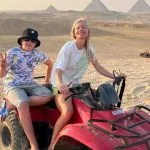 A mother and son smiling on a red vehicle during their quad bike around pyramids family trip
