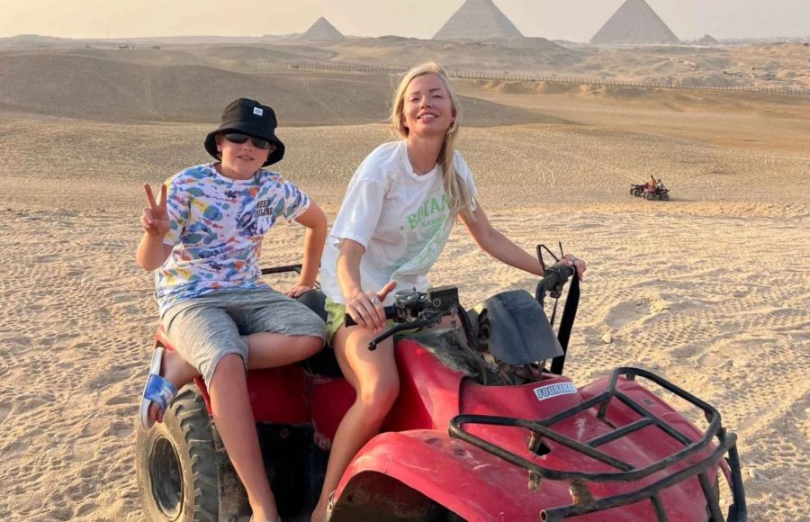 A mother and son smiling on a red vehicle during their quad bike around pyramids family trip