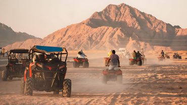 Tourists on quad bikes and buggies in the desert with mountains in the background, a popular adventure thing to do in Egypt.