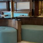 Modern seating area with green poufs and wooden counter in a ship's lobby.