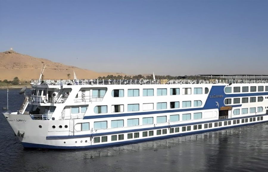 White and blue Nile cruise ship sailing past a sandy bank.