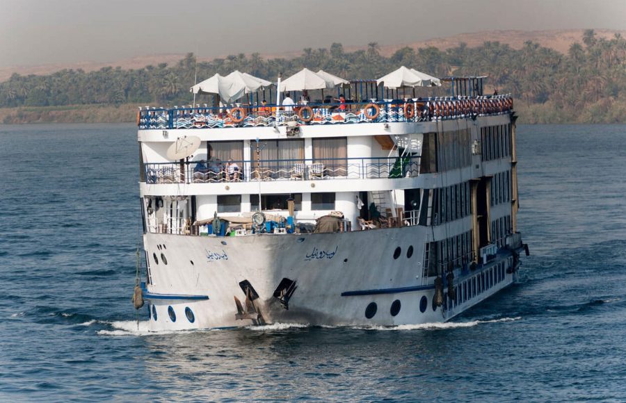 A large, multi-story River Nile Cruise ship River Nile Egypt Africa floats on blue water, a key part of any 12 days egypt tour.