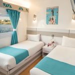 Twin bed cabin with turquoise accents and a large window facing the Nile.