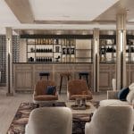 Modern cruise ship bar and lounge area with light wood paneling, a bar counter, and various seating groups with velvet upholstery.