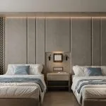 Luxury twin-bed cruise cabin with a large upholstered headboard, a central nightstand, and subtle ambient lighting.