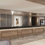 Long, wood-paneled cruise ship reception counter with a black top, framed by patterned screens and Egyptian-themed artwork.