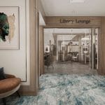Entrance to the "Liberty Lounge" on a cruise ship, featuring an abstract blue carpet, wood paneling, a seating area, and a large portrait of an Egyptian queen.
