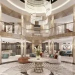 Multi-story luxury cruise lobby with a central chandelier, marble floor with a radial pattern, and modern lounge seating areas.