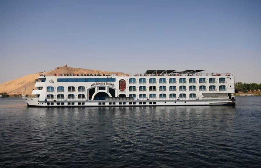 Long shot of the MS Royal Ruby Nile cruise ship with a desert hill in the background.