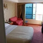 Cruise ship cabin with large window overlooking the Nile, a bed, couch, and TV.
