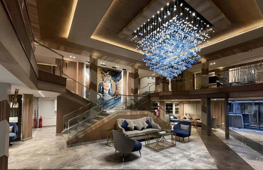 Grand atrium and reception area of MS Royal Signature with a large blue crystal chandelier and a mural.