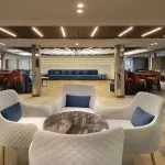 Luxurious lounge on MS Royal Signature cruise ship with white armchairs, blue seating, and modern lighting.