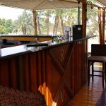 An outdoor wooden bar on the sundeck of the Royal Viking Nile Cruise with a view of palm trees in the background.