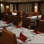 The formal dining room of the Royal Viking Nile Cruise with set tables and red napkins.