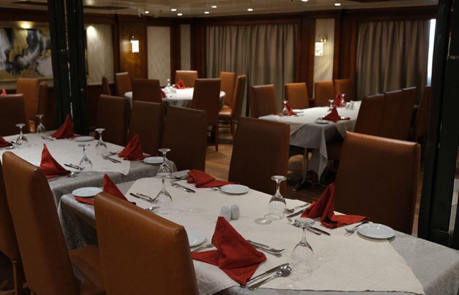 The formal dining room of the Royal Viking Nile Cruise with set tables and red napkins.