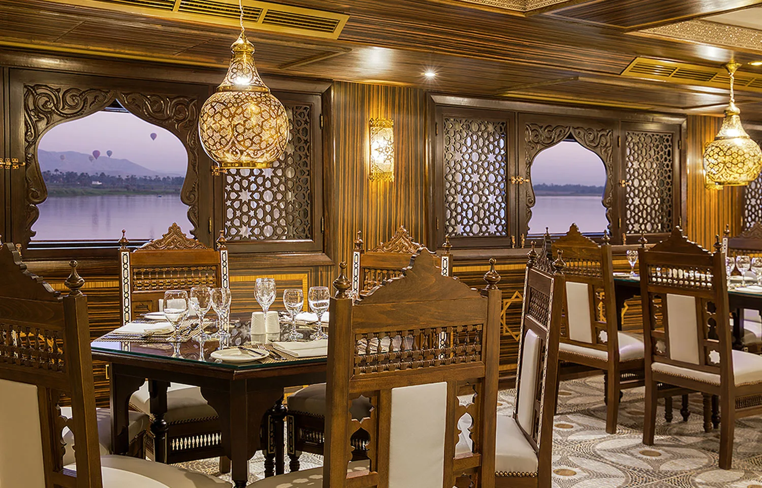 The luxurious restaurant on the Sphinx Nile Cruise with ornate wooden chairs and scenic Nile views at sunset