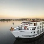 An exterior view of the luxurious SS Sphinx Nile Cruise ship sailing peacefully at sunset