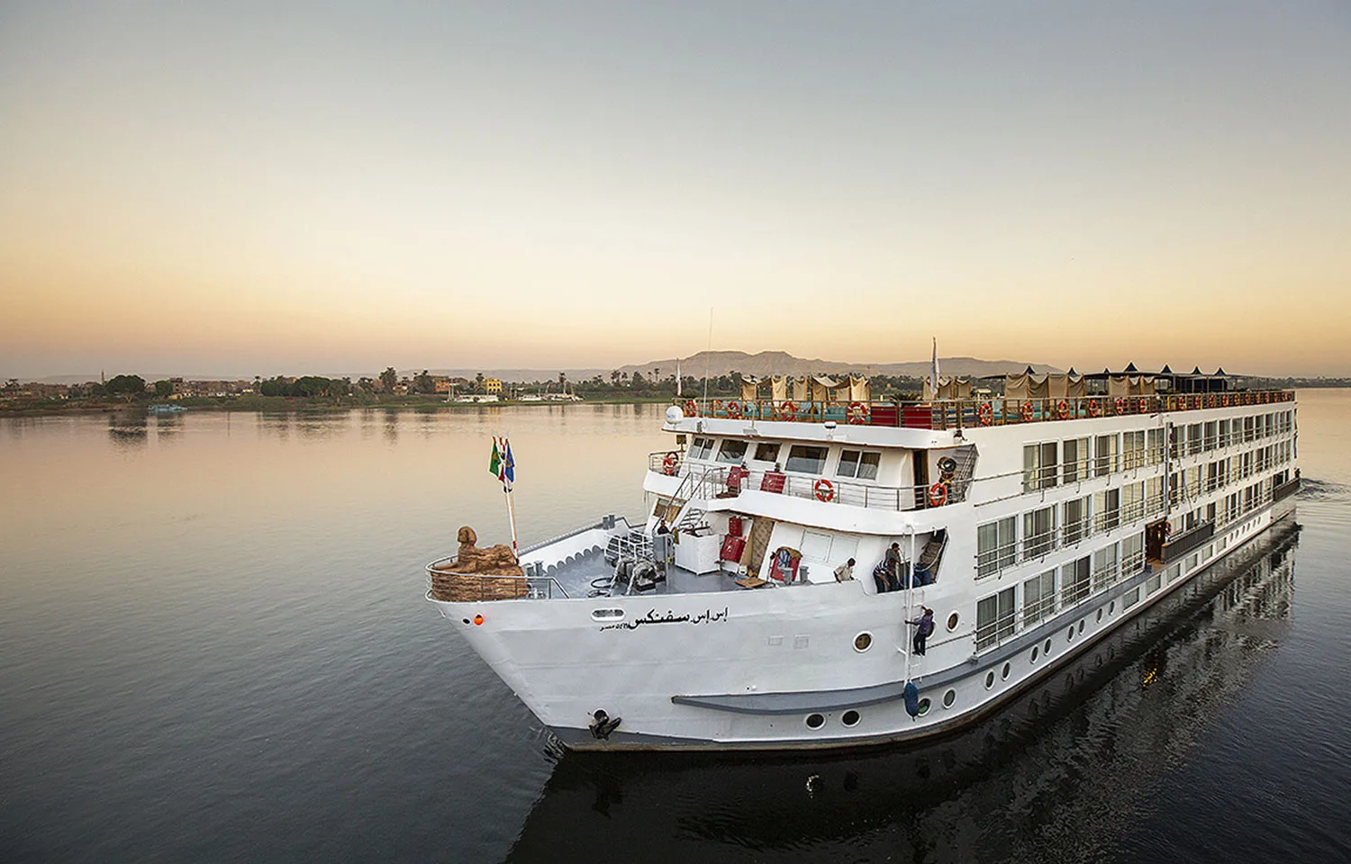 An exterior view of the luxurious SS Sphinx Nile Cruise ship sailing peacefully at sunset