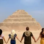 Friends holding hands in front of the monument on a Saqqara Step Pyramid tour