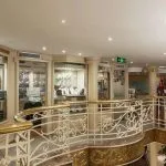 Onboard shopping center with jewelry displays and clothing racks near a curved staircase.