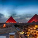 A breathtaking panoramic view of the pyramids light show Cairo featuring the Giza plateau glowing under a deep blue twilight sky