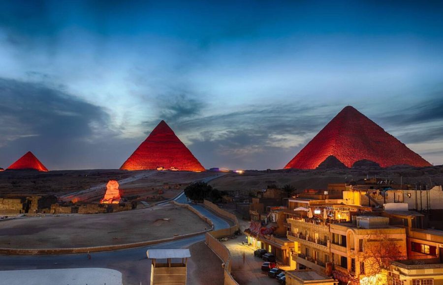 A breathtaking panoramic view of the pyramids light show Cairo featuring the Giza plateau glowing under a deep blue twilight sky