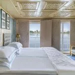 Royal Suite cabin with a plush bed and large windows overlooking the Nile River on the luxurious Sphinx Nile Cruise