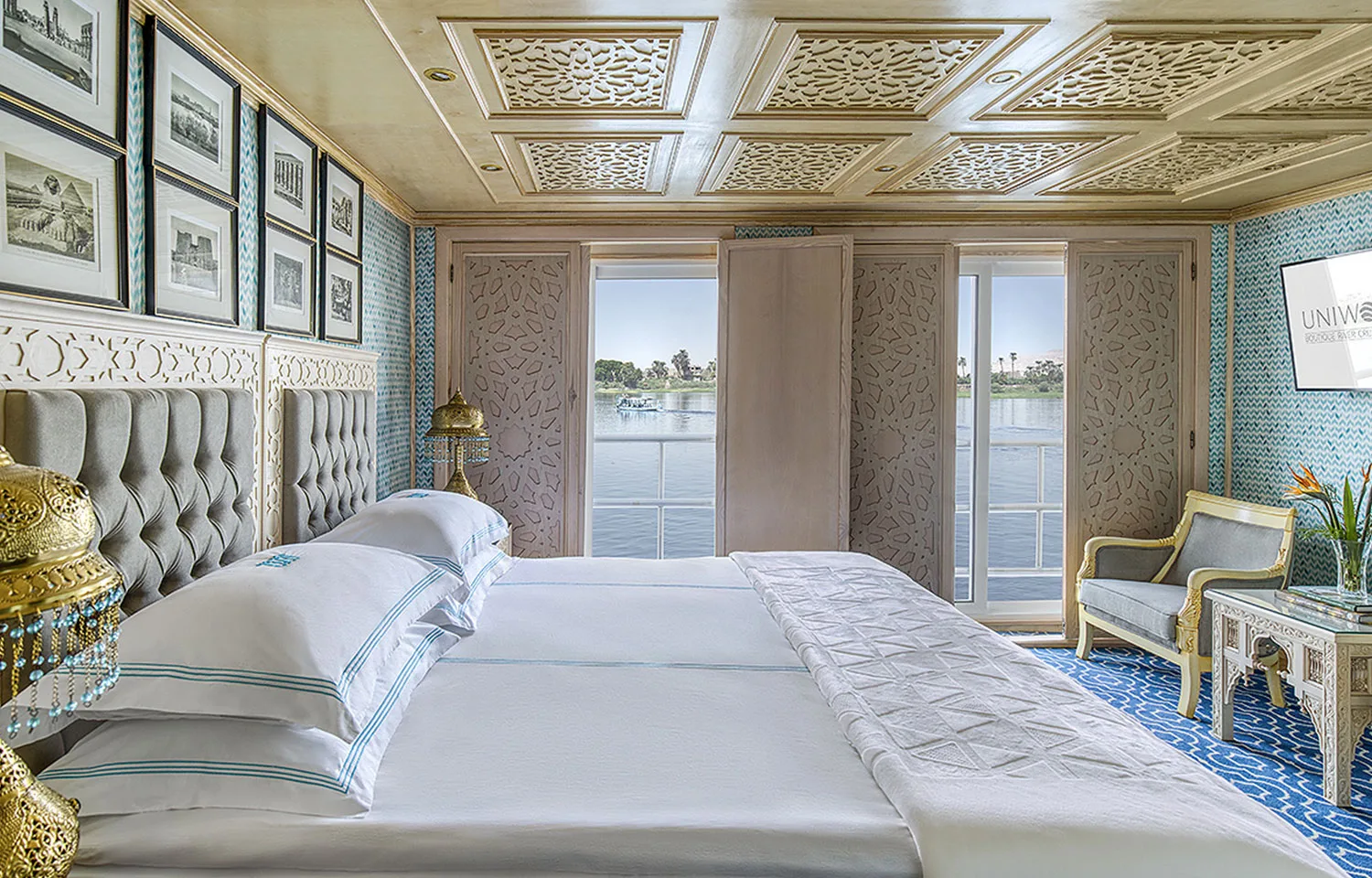 Royal Suite cabin with a plush bed and large windows overlooking the Nile River on the luxurious Sphinx Nile Cruise