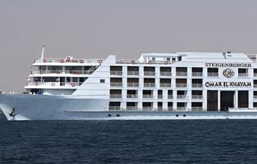 A large, white multi-deck luxury cruise ship named Steigenberger Omar El Khayam sailing on the water.