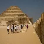 Tourists walk along the perimeter wall approaching the Step Pyramid of Saqqara tour