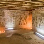 An interior view of the Temple of Ain El Muftella in Bahariya oasis Egypt Western Desert, showing well-preserved ancient wall relief carvings and a wooden plank roof.