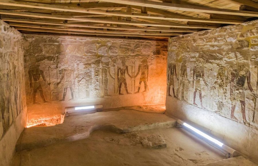 An interior view of the Temple of Ain El Muftella in Bahariya oasis Egypt Western Desert, showing well-preserved ancient wall relief carvings and a wooden plank roof.