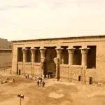 The ancient Temple of Khnum in Esna, featuring a grand facade with massive sandstone columns under a bright sky.