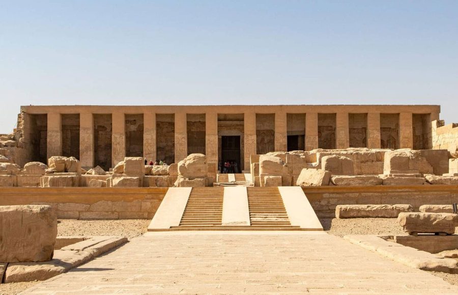 The grand, multi-columned facade and stepped entrance of the Temple of Seti I Abydos in Upper Egypt, a large ancient stone structure in the desert.