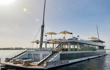 Full view of the Kazazian Arax Dahabiya on the Nile with white sun umbrellas and glass railings