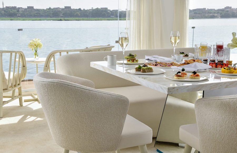 A gourmet breakfast spread on a white marble table overlooking the Nile River.