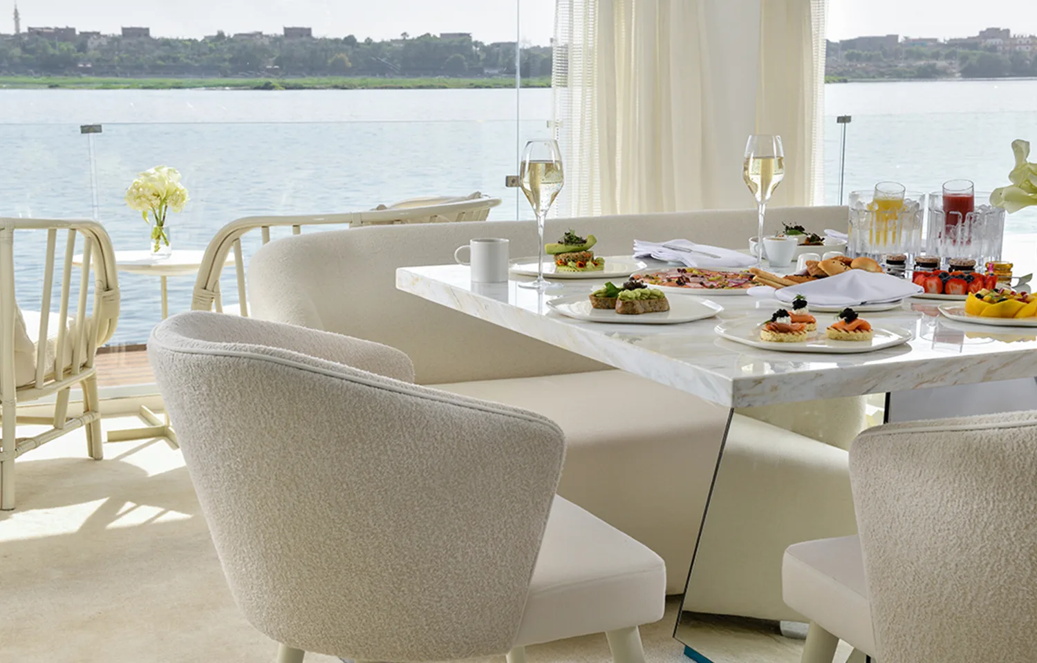 A gourmet breakfast spread on a white marble table overlooking the Nile River.