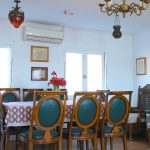 A classic indoor dining room with a wooden table, teal upholstered chairs, and antique décor.