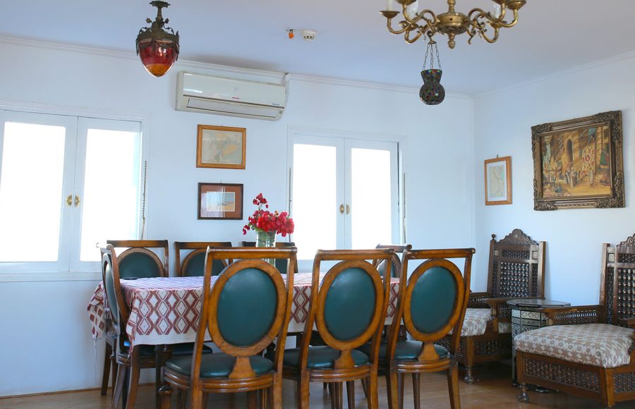 A classic indoor dining room with a wooden table, teal upholstered chairs, and antique décor.