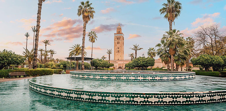 The majestic Koutoubia Mosque rises above a serene fountain in Marrakech Morocco bathed in the warm glow of the setting sun