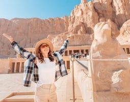 Tourist at Hatshepsut Temple, part of tour packages from Toronto to Egypt. A happy tourist posing in front of the Hatshepsut Temple, a key destination in Egypt vacation packages from Toronto.