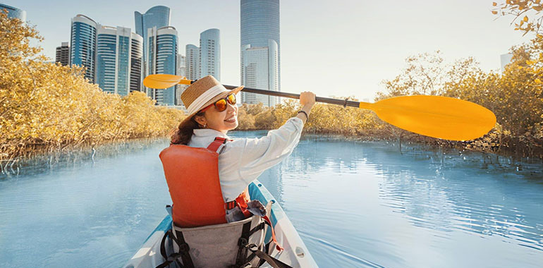 Tourist paddling on a kayak in mangrove lagoon park in Abu Dhabi United Arab Emirates