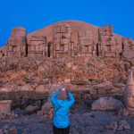Tourist-photographing-statues-at-sunrise-on-the-eastside-of-the-mountain-Mt-Nemrut-Turkey